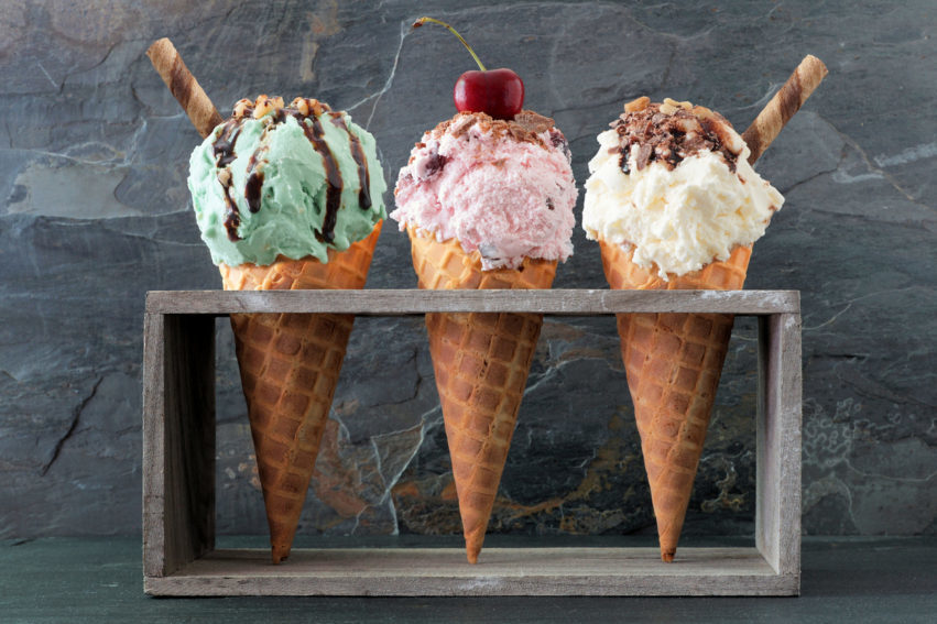 Pistachio, cherry and vanilla ice cream in waffle cones over slate