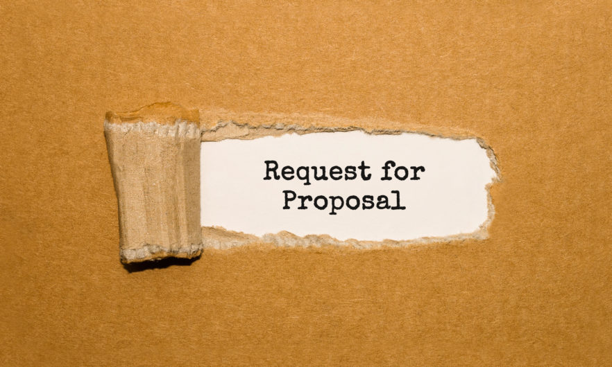 The text Request for Proposal appearing behind torn brown paper