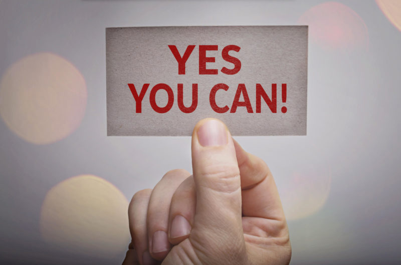 Yes you can! motivational card in hand with bokeh lights background